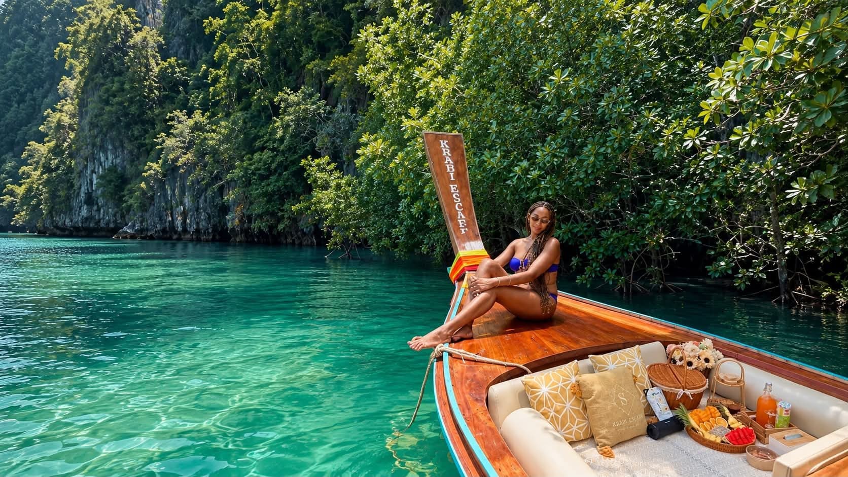Guest relaxing on the bow of a Krabi Escape longtail boat beside a limestone lagoon with a picnic set on board
